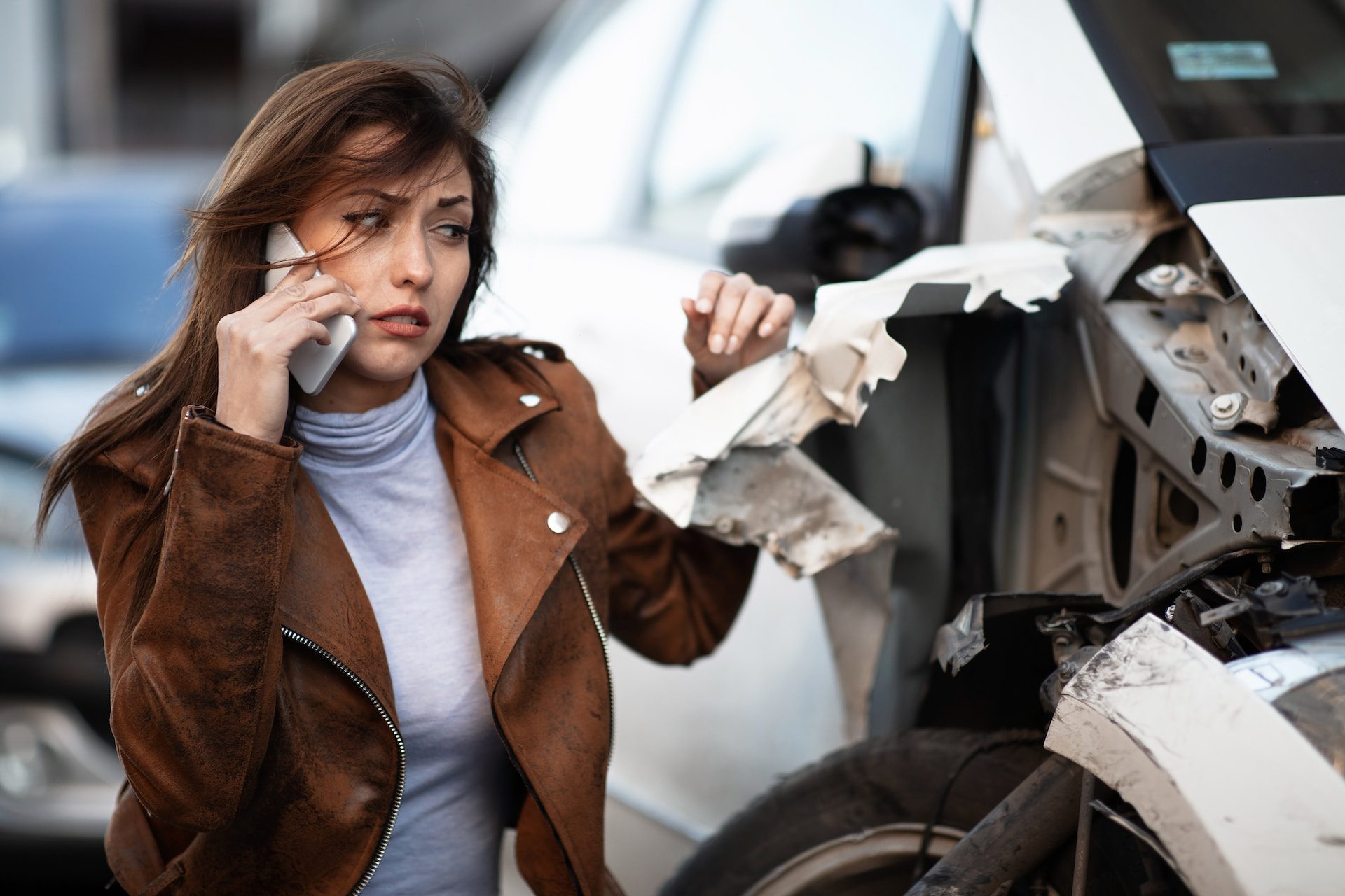 woman on the phone while looking at car damage